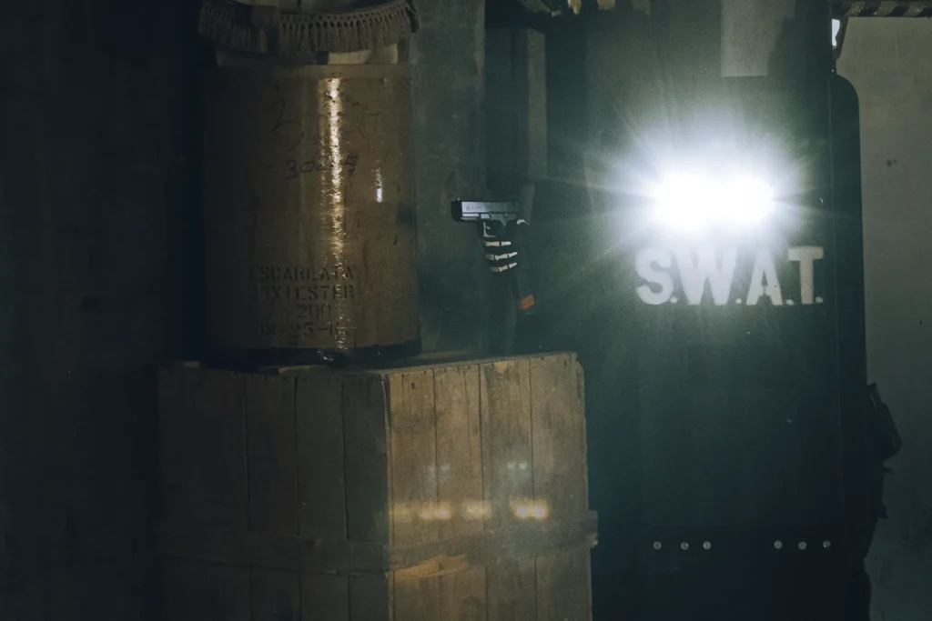 Jugador avanza en un escenario CQB iluminando el espacio con linterna táctica. Máxima tensión y concentración en una situación CQB de corta distancia.